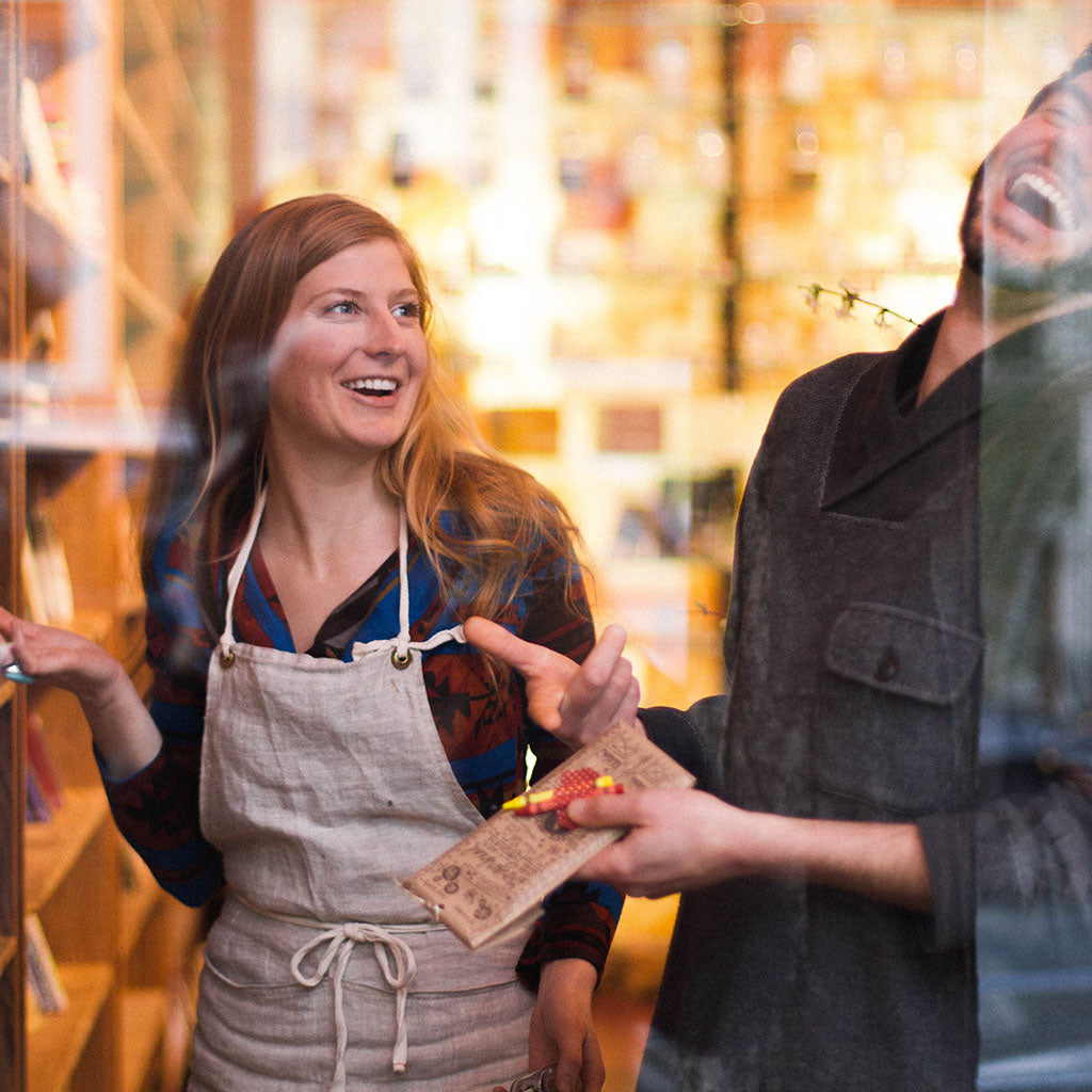 Two shop keepers laugh together inside the meadow