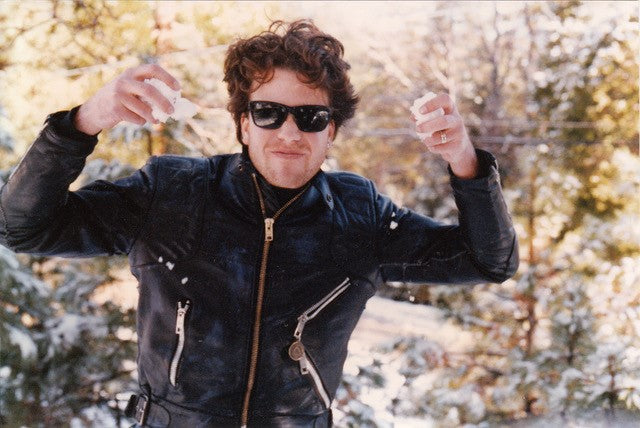 Mark Bitterman wearing a leather jacket, holding up chunks of salt in both hands