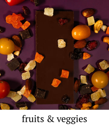 Chocolate bar with various fruits and vegetables on a purple background
