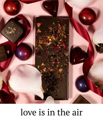 Chocolate bar with decorative elements on a pink background with text 'love is in the air'.