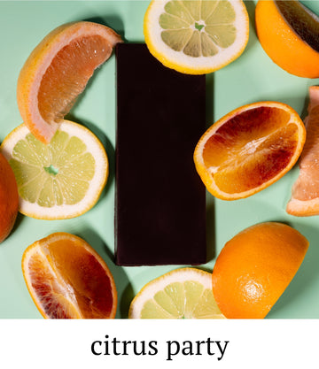 Dark chocolate bar surrounded by sliced citrus fruits on a light green background with 'citrus party' text.