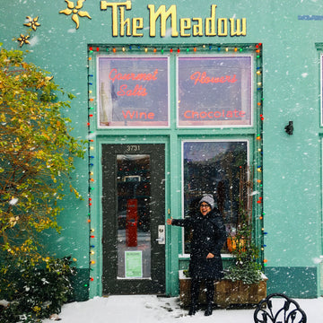 Person standing outside a building named 'The Meadow' on a snowy day Mississippi shop