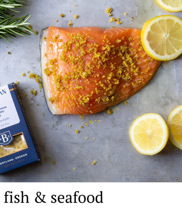 Salmon fillet with lemon and rosemary on a gray surface, with a B&G Foods package in the background.