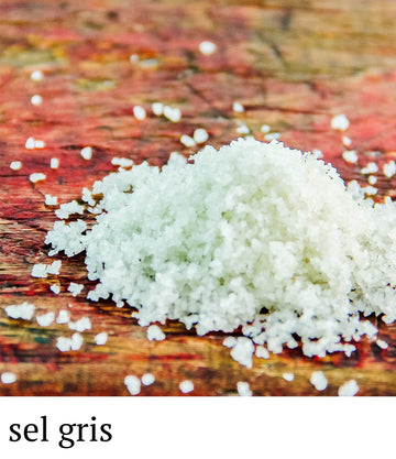 White sea salt on a wooden surface with 'sel gris' text