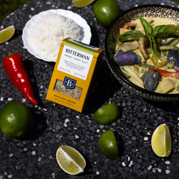 Bitterman's Green Curry Salt with limes rice and bowl of green curry on black stone