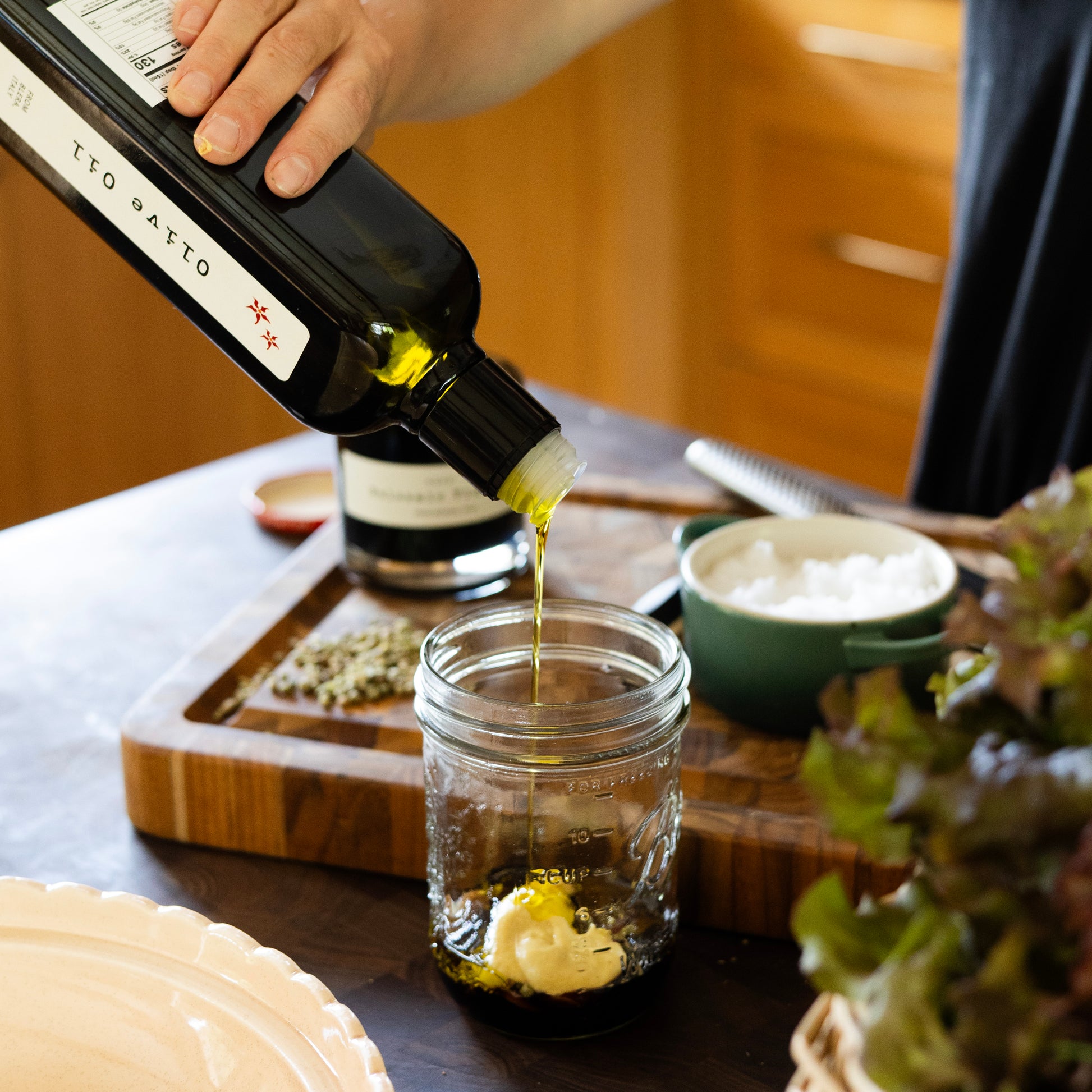 olive oil being poured into mason jar making a vinaigrette
