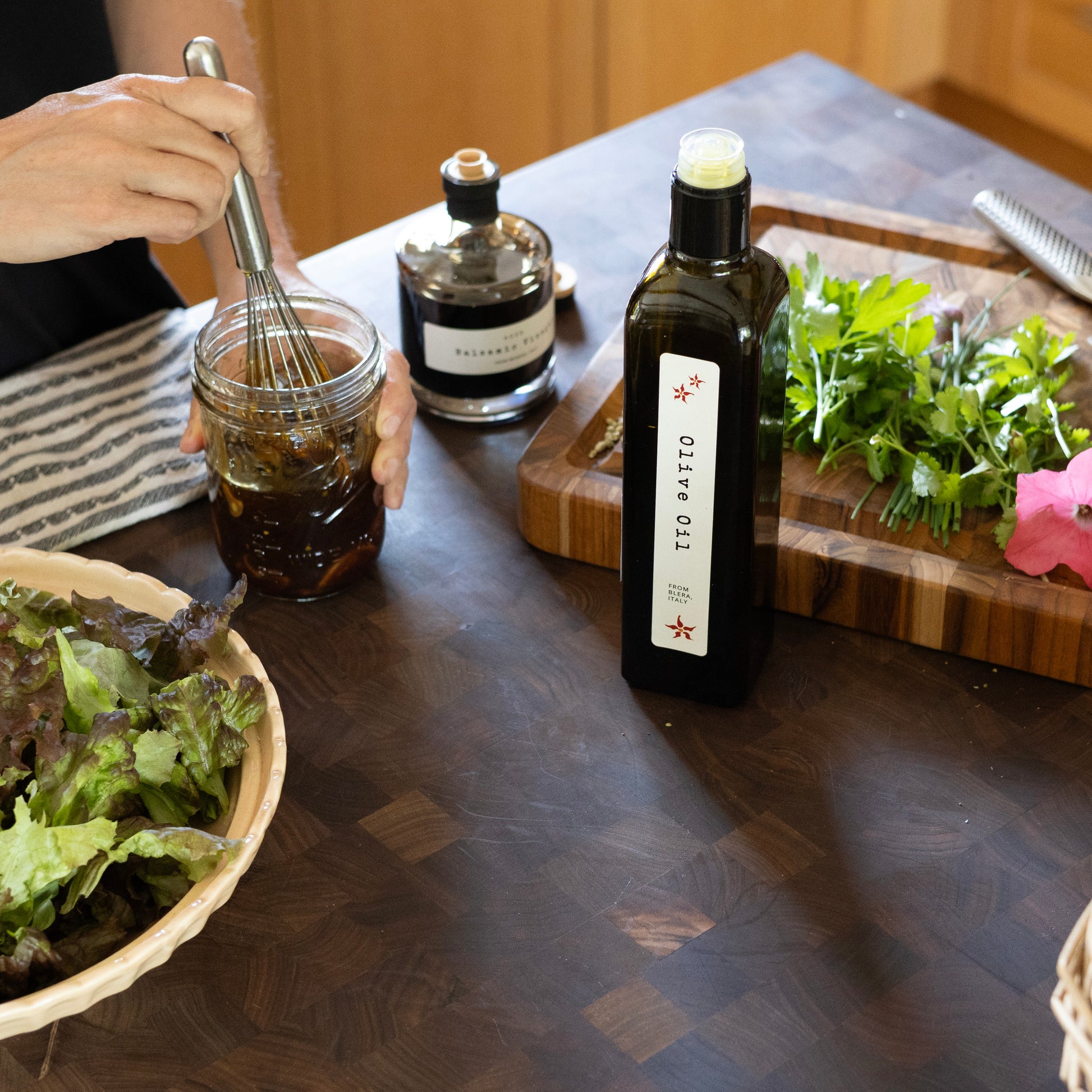 whisking a vinaigrette in a mason jar next to a salad