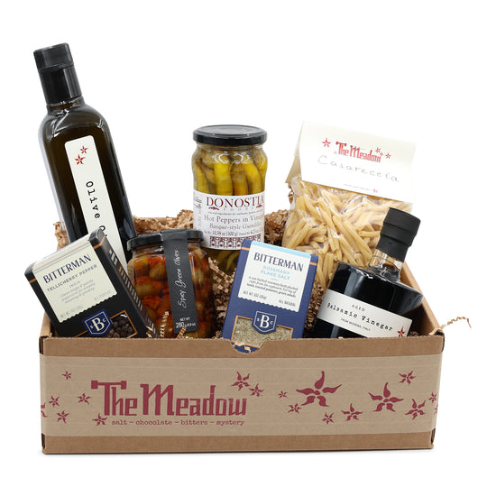Gift basket from 'The Meadow' with various food items including bottles and jars on a white background.