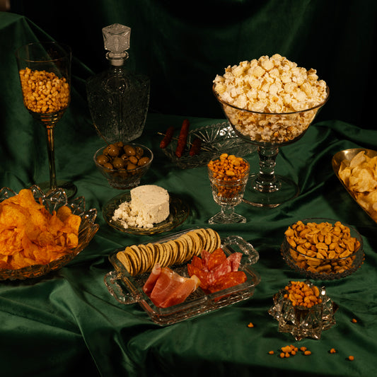 Assorted snacks including popcorn, olives, and crackers on a green tablecloth.