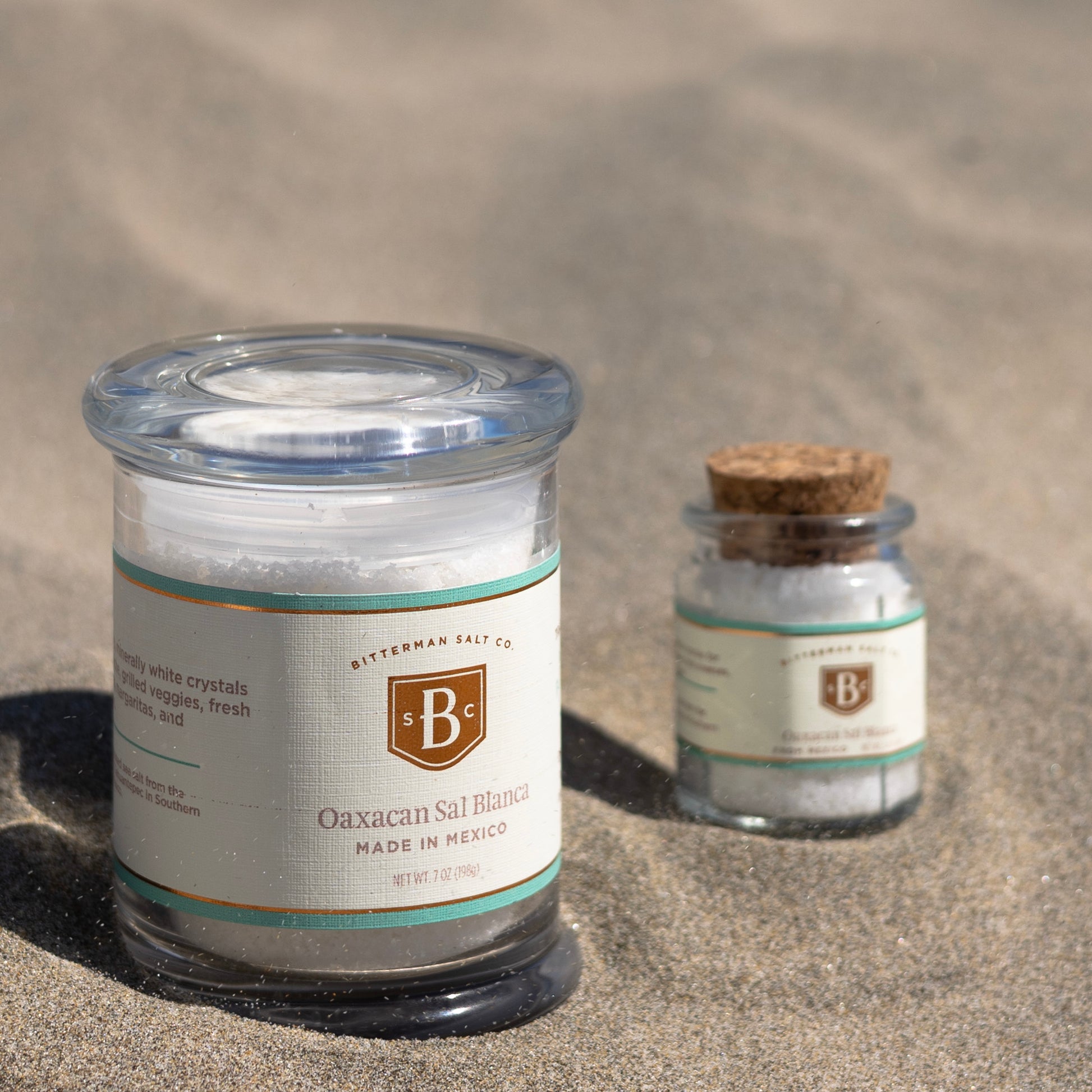 Two jars of Bitterman's salt on a sandy surface
