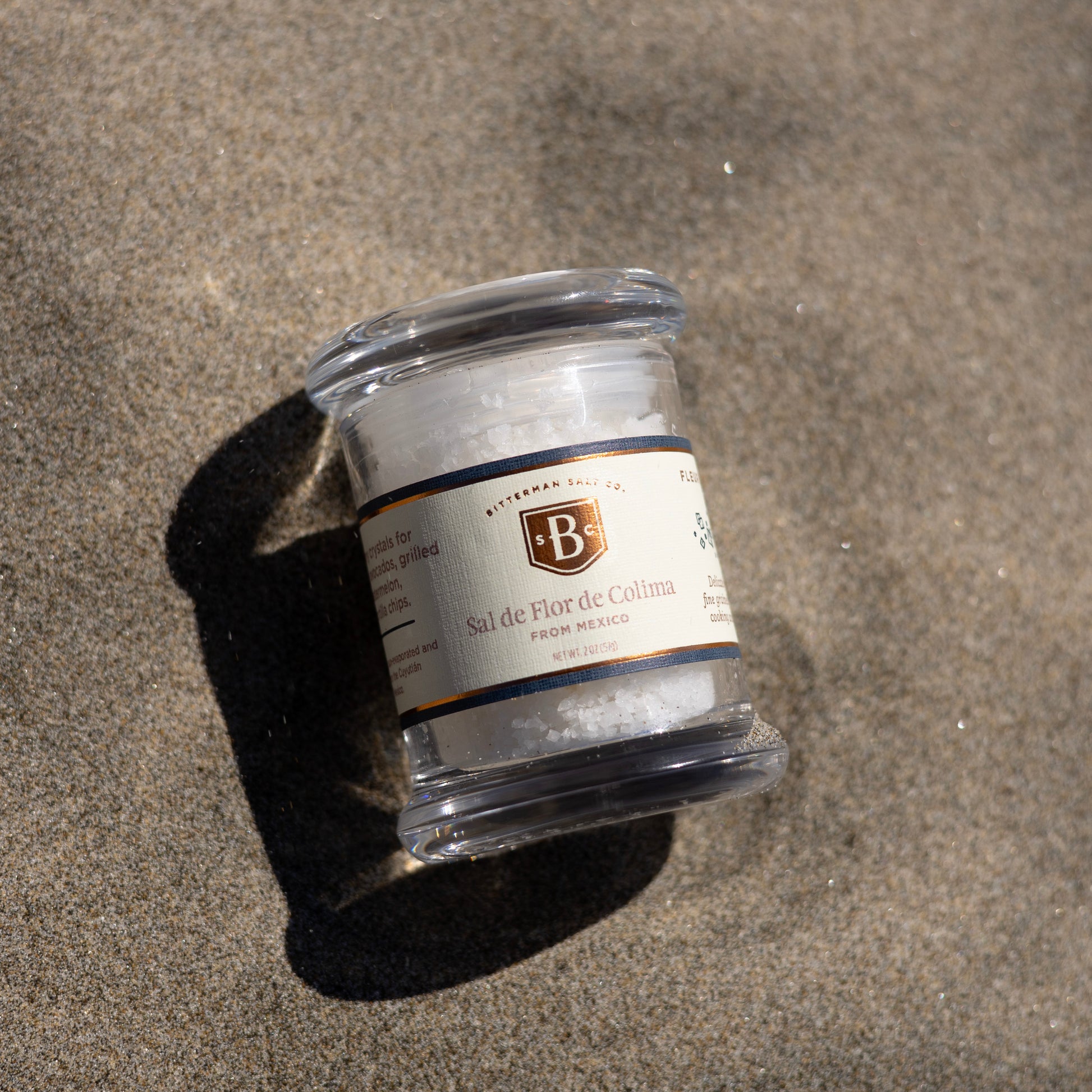 Jar of salt with a label on a sandy surface