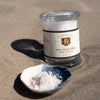 Jar of Bitterman's Salt Co. salt on sand with a small dish of salt next to it.