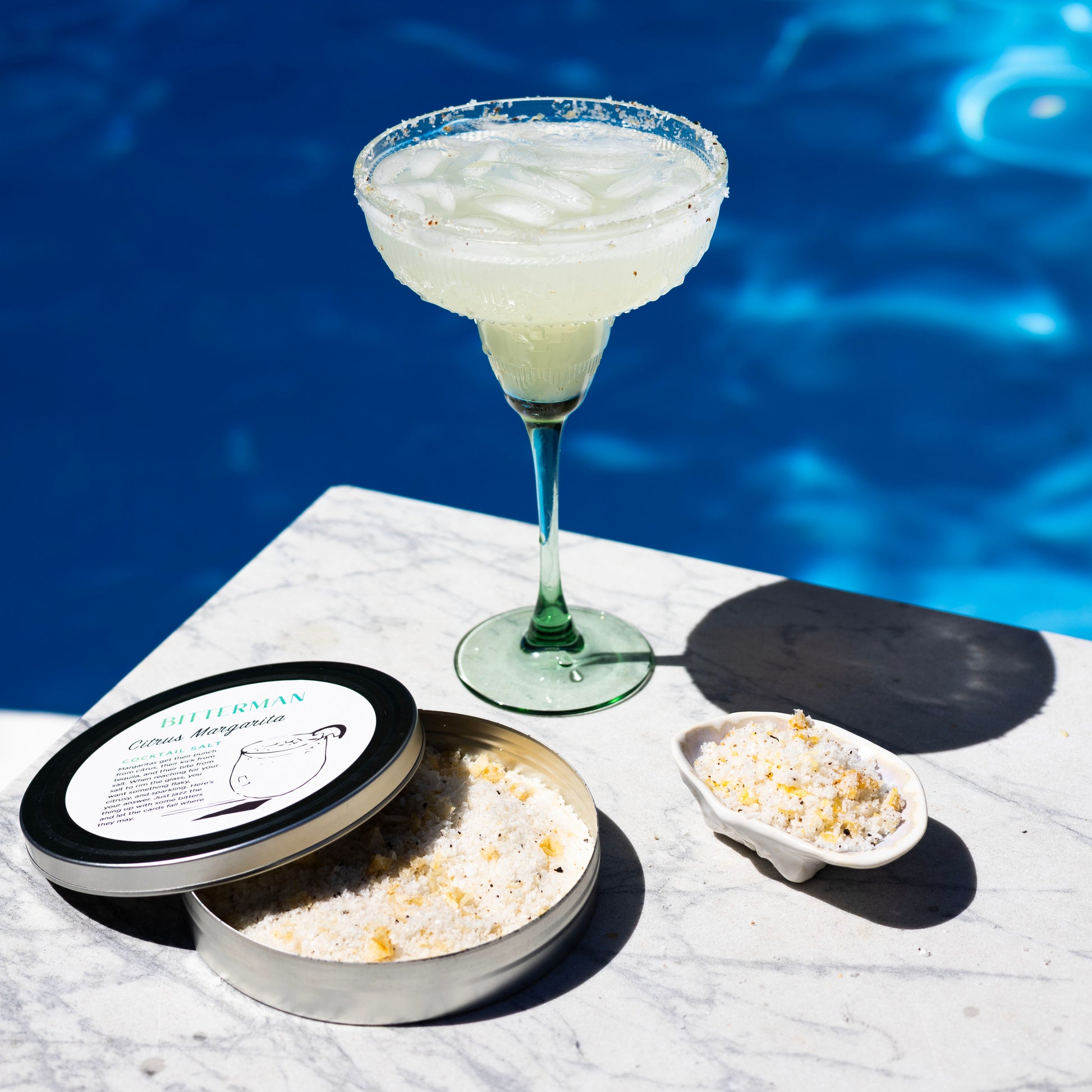Cocktail with salt and garnish on a poolside table