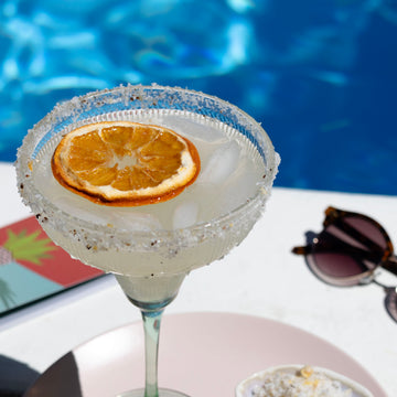 margarita with dried orange garnish with salted rim by pool