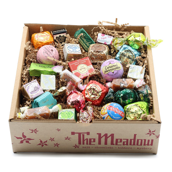 Assorted candies in a box labeled 'The Meadow' on a white background