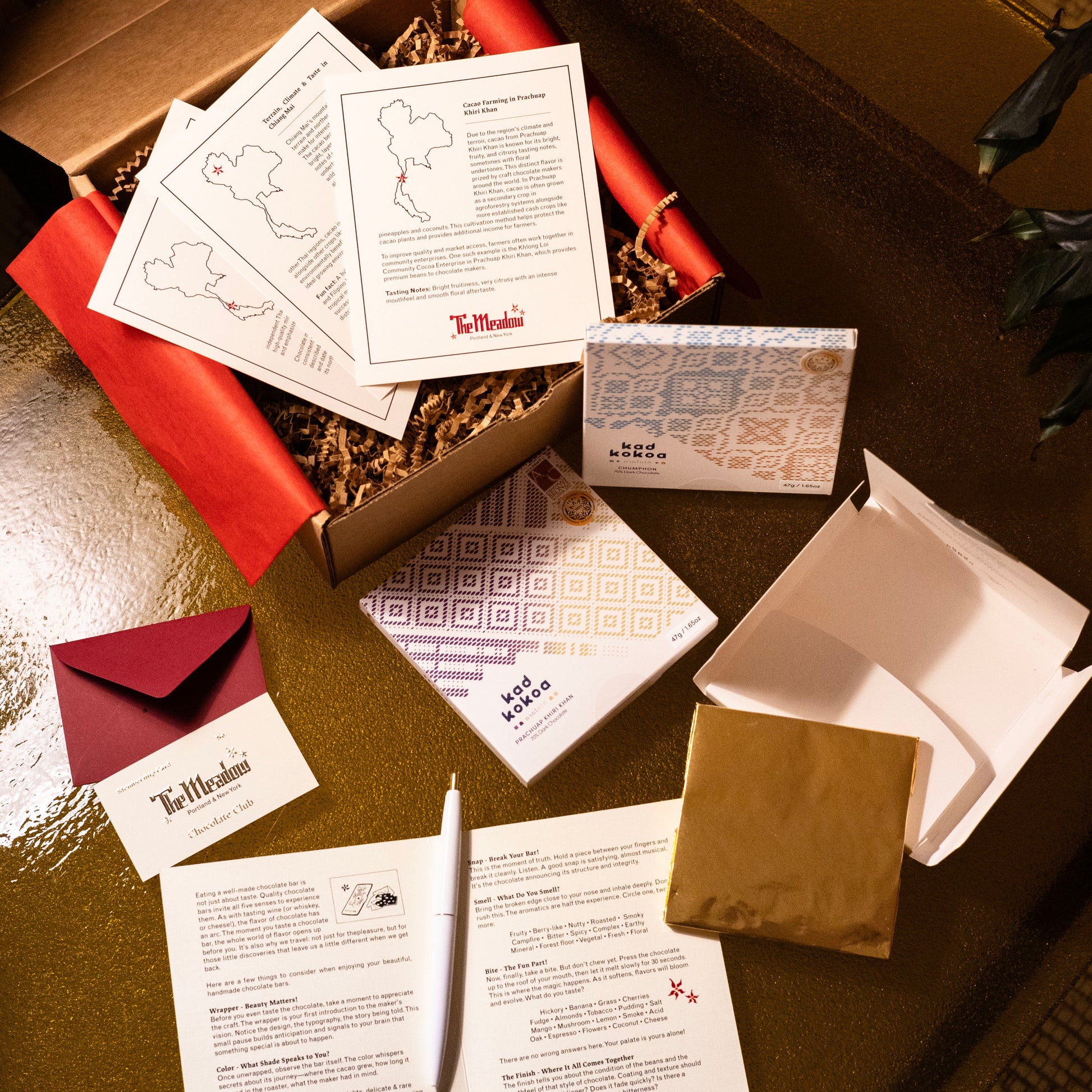 Unboxing experience of chocolate club with branded materials and packaging on a golden surface surface