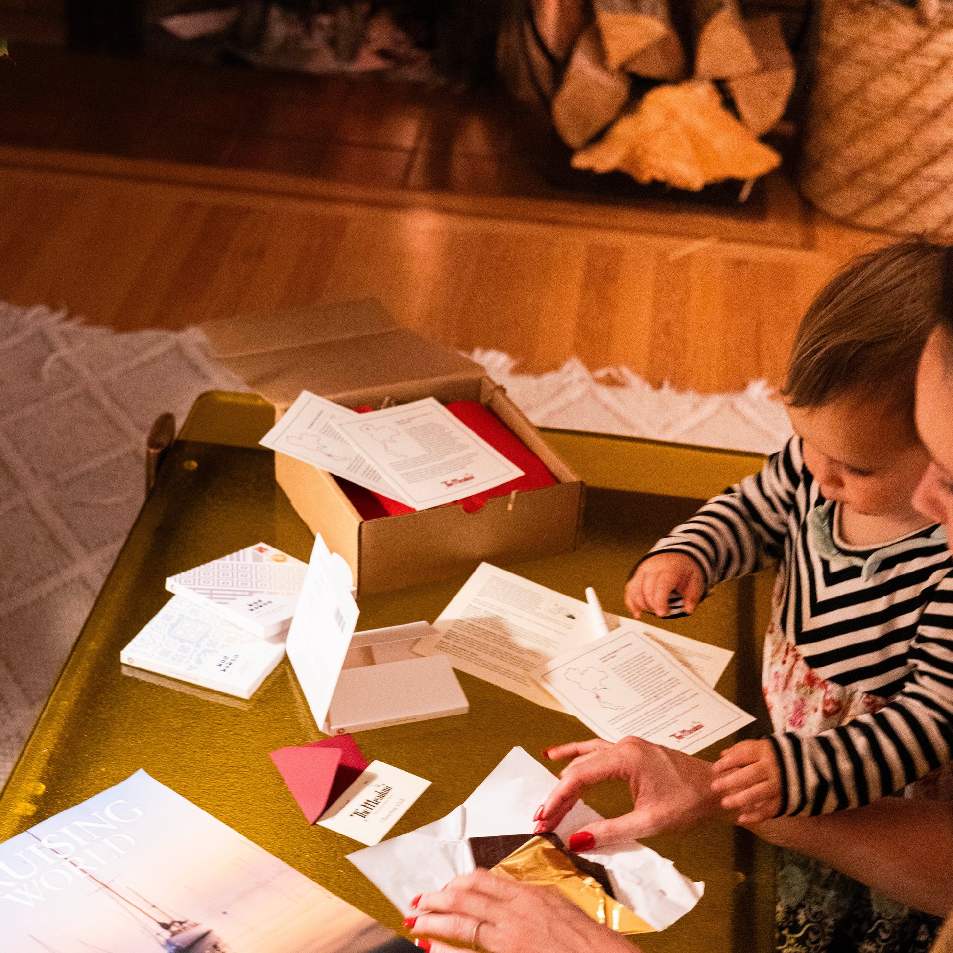 Woman and child unboxing The Meadow's chocolate club on a table with a fireplace in the background