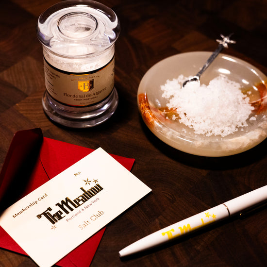 salt club contents: salt in a jar, bowl of salt, and membership card on a wooden surface