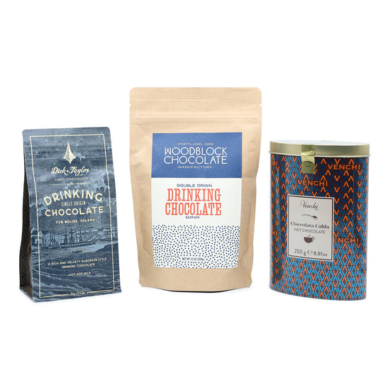 Three packages of drinking chocolate from different brands on a white background