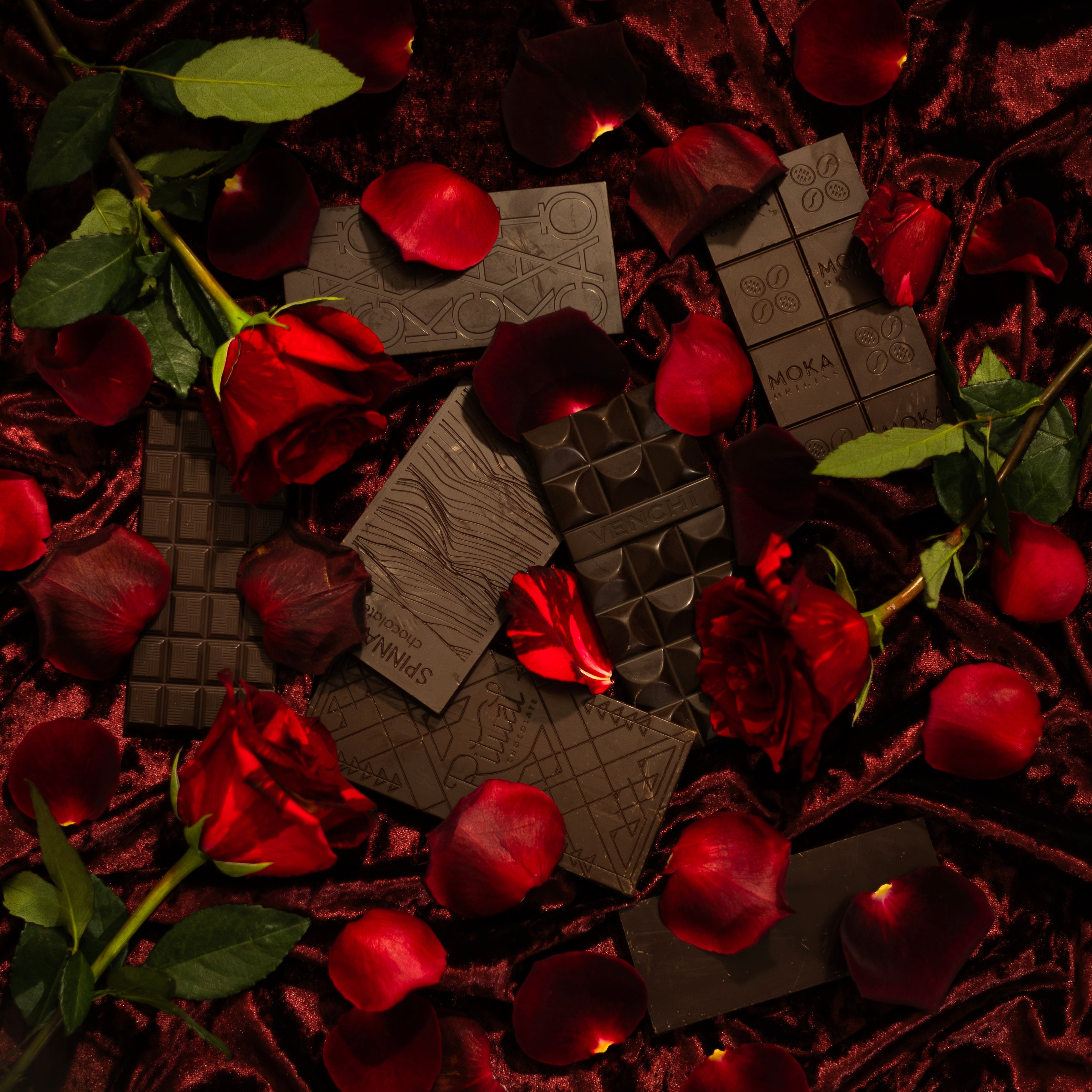 dark chocolate bars surrounded by red roses and petals