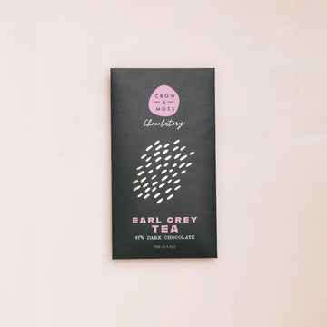 Dark chocolate bar packaging with 'Crow & Moss Chocolatery' branding on a light pink background