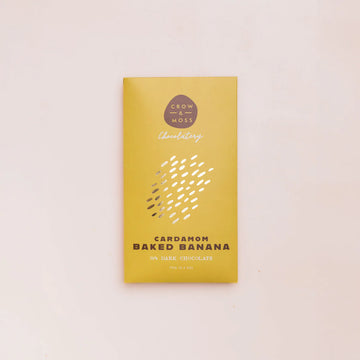 Yellow chocolate bar packaging with 'Crow & Moss Chocolatery' branding on a light pink background