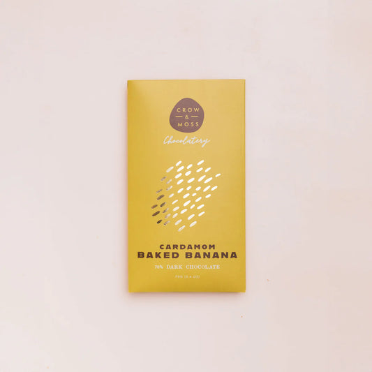 Yellow chocolate bar packaging with 'Crow & Moss Chocolatery' branding on a light pink background