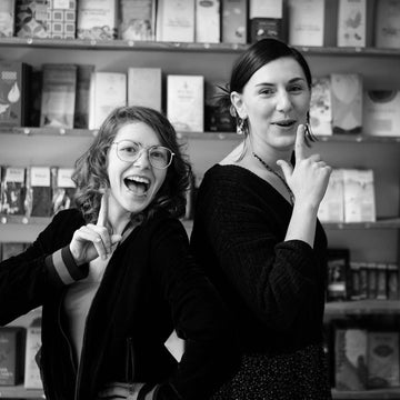 Shopkeepers Christiana and Charlotte pose in front of chocolate wall