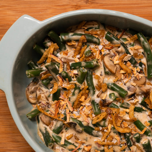 Green bean casserole with mushrooms and onions and crispy shallot salt in a gray dish on a wooden surface