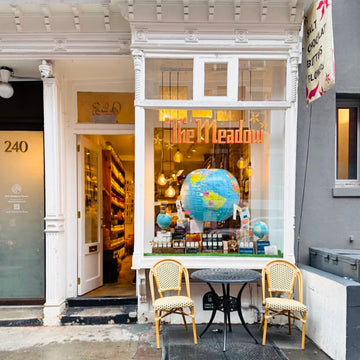Mulberry Storefront with 'The Meadow' sign, globe decorations, and chairs outside.