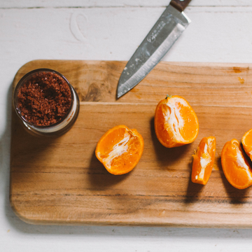 Sliced oranges on a wooden cutting board with a jar of haleakala red sea salt